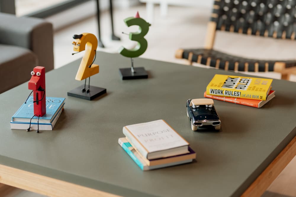 Uma mesa de centro com figuras decorativas com forma dos números 1, 2 e 3, assim como alguns livros e um pequeno carro de brinquedo.